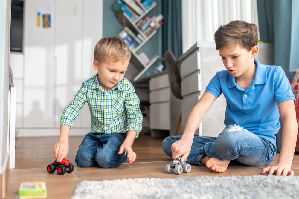 Two siblings playing with model cars